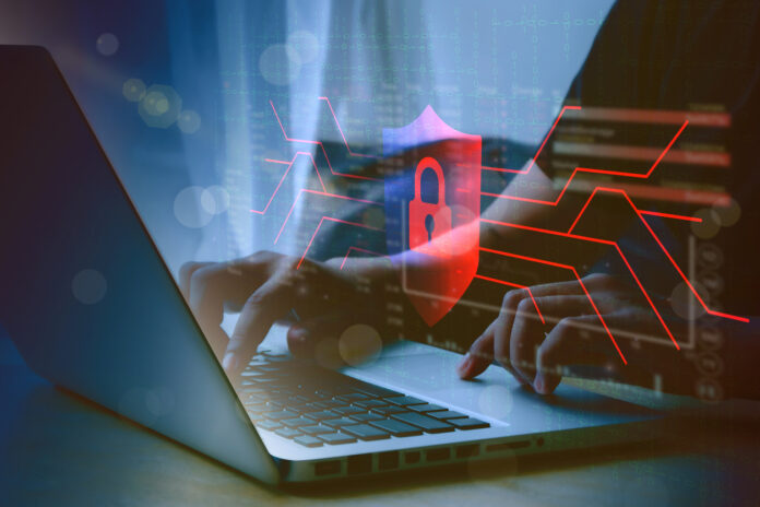 Person’s hands typing on a laptop overlaid with a cybersecurity design.