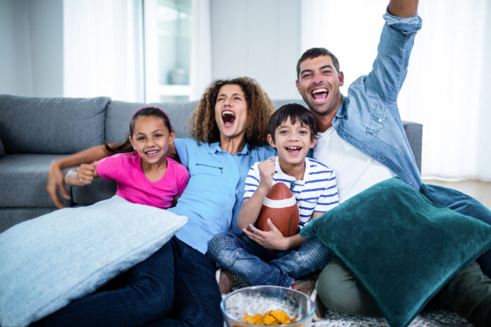 Family watching american football match on television A family sitting on the couch at home while watching NFL football on TV