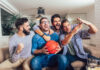 A group of male friends watching the March Madness men’s basketball tournament on TV at home.
